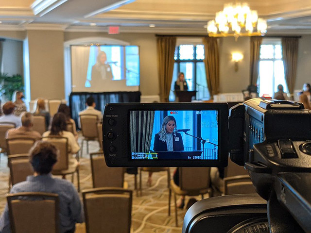 Camera showing a woman speaking at an Chicago Country Club
