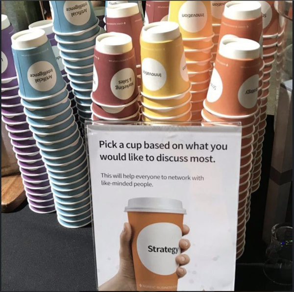 stacked multicolored networking coffee cups with different conversation topics printed on them