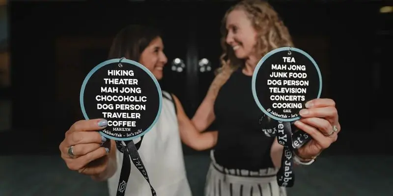 two women holding conference badges with a list of personal interests