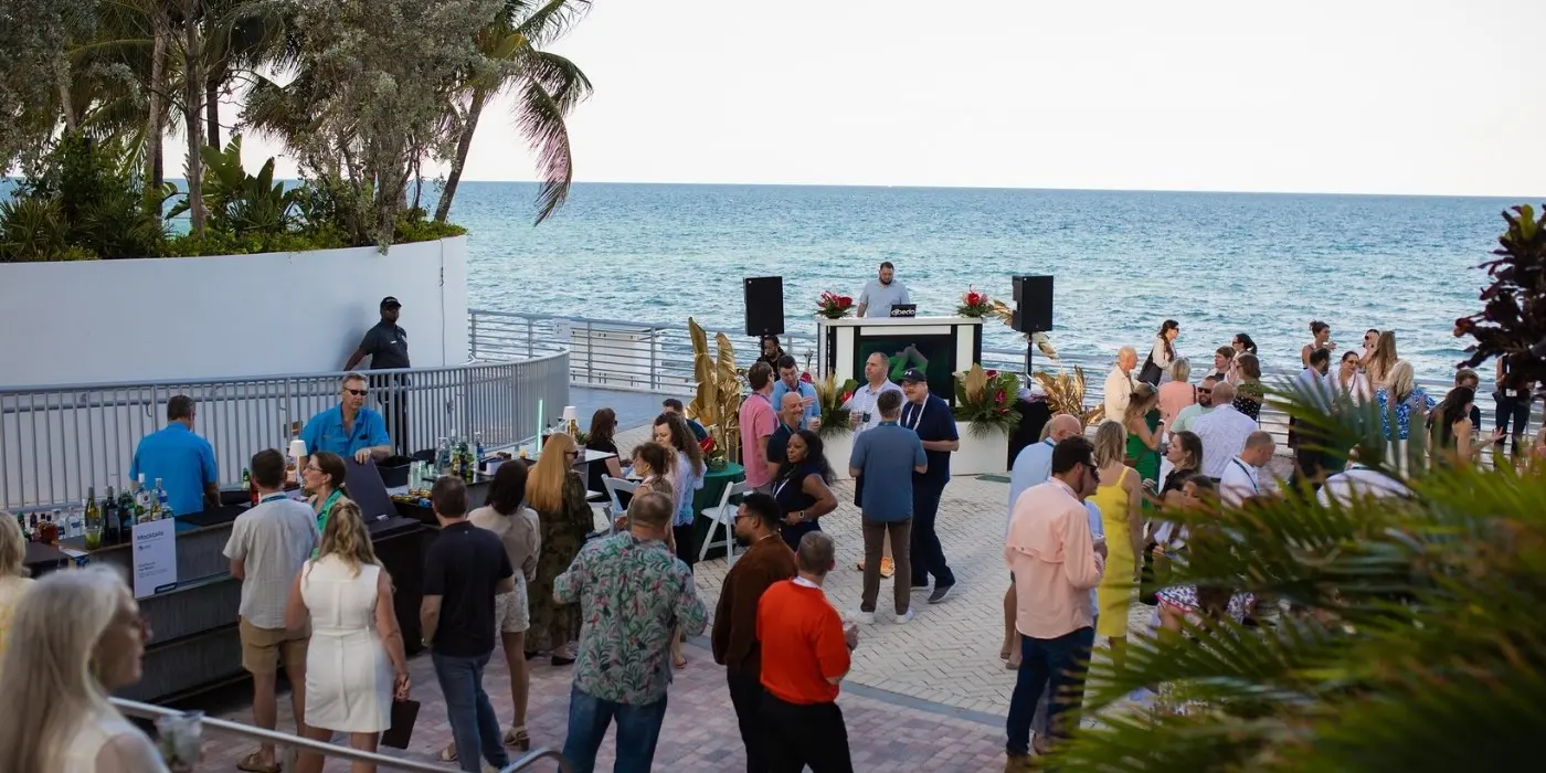 Conference attendees networking at outdoor oceanside reception