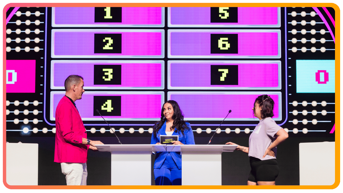 Host and contestants on a corporate event game show stage