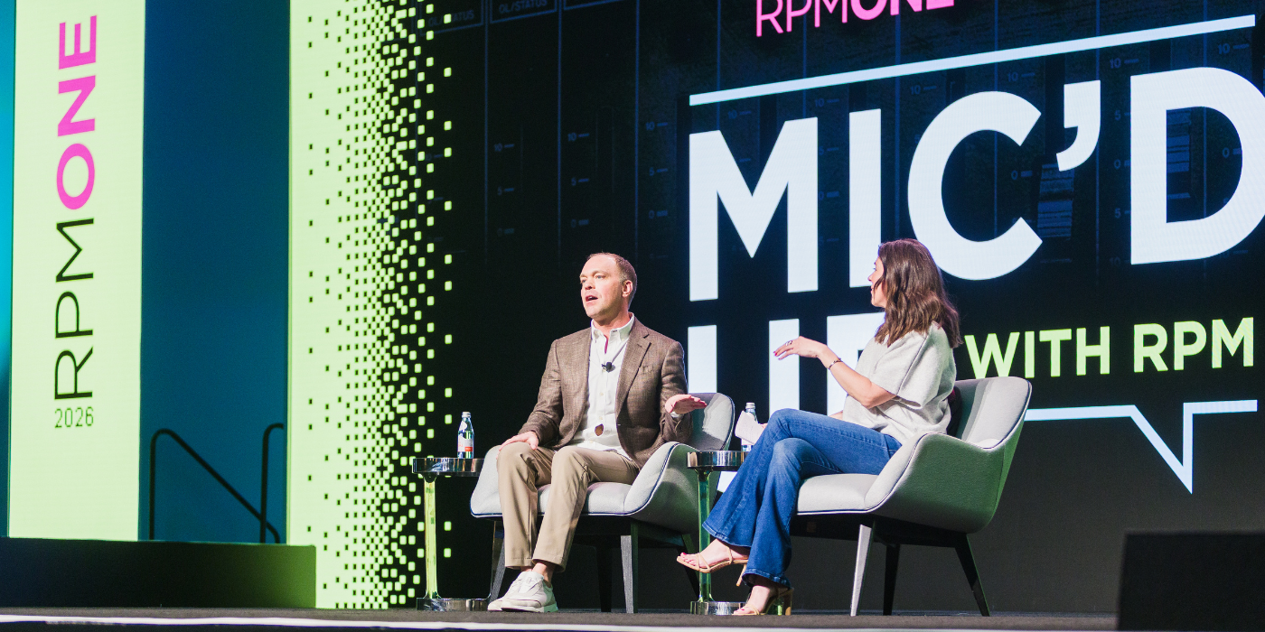 Two speakers in conversation on a branded conference stage