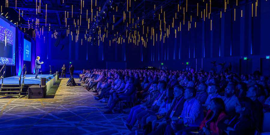 Large corporate conference general session audience with blue lighting