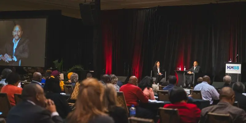 Two speakers on stage at a branded executive conference